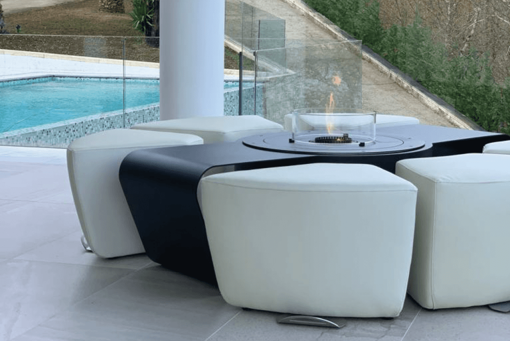 Circus fire pit with gas, bioethanol, and wood options, featuring white benches by the pool in a luxury outdoor setting