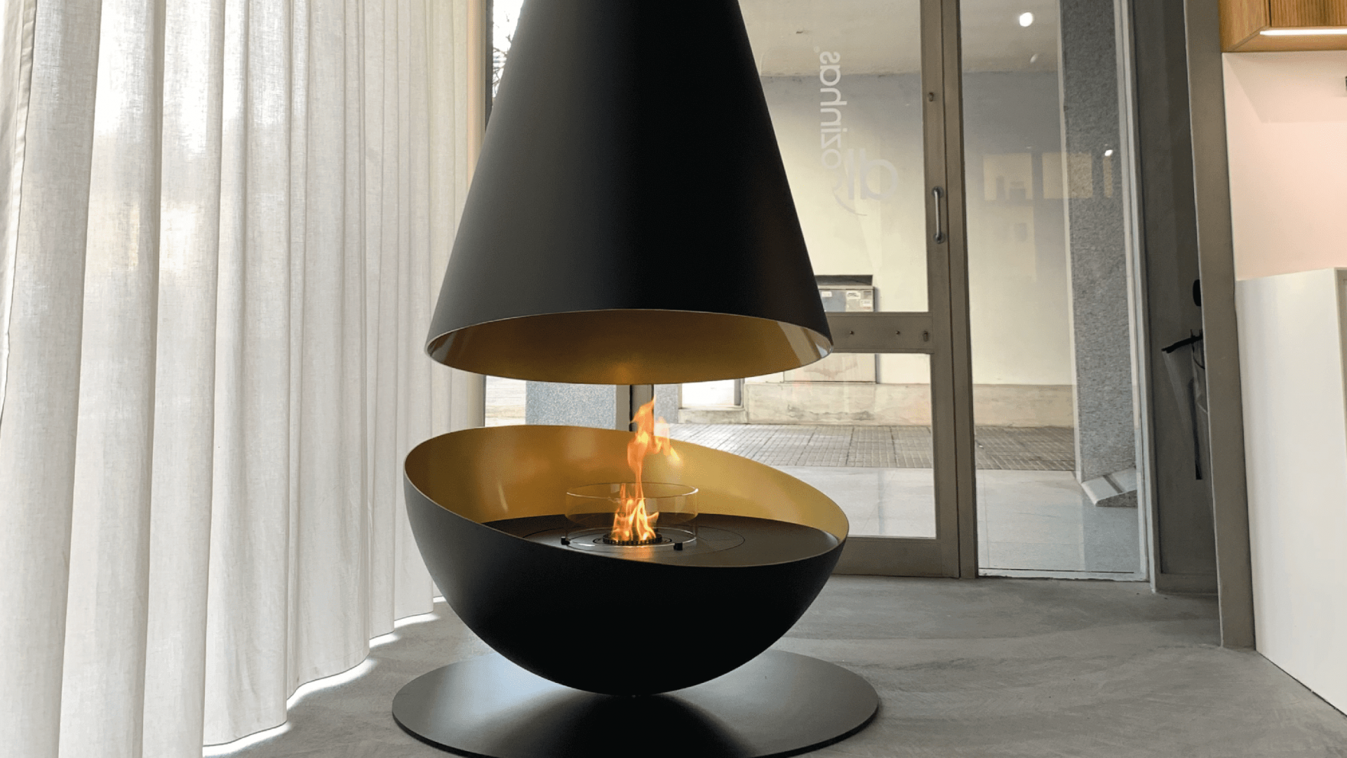 Thales suspended bioethanol fireplace by GlammFire with black and gold design in a modern interior setting